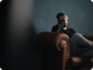 A stressed man sitting on a leather armchair.