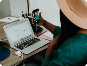 A woman at a desk using her laptop and phone.